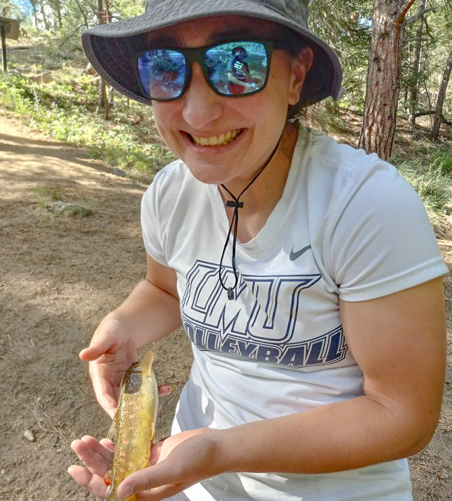 Lydia is outdoors holding a long fish.