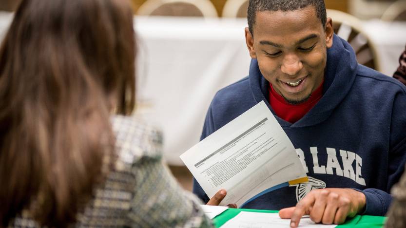 Student smiling and reading through papers