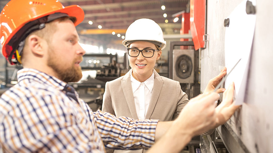 Two people in a warehouse reviewing plans