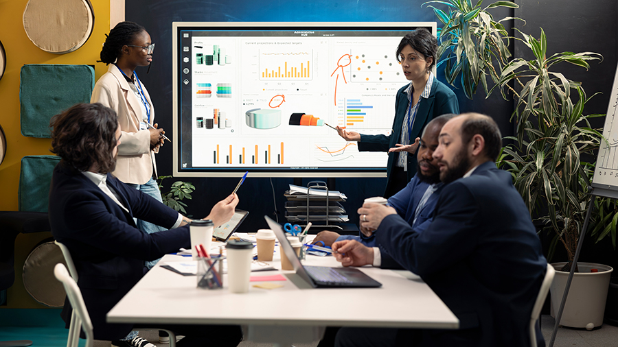 A team around a conference table reviewing data on a large monitor